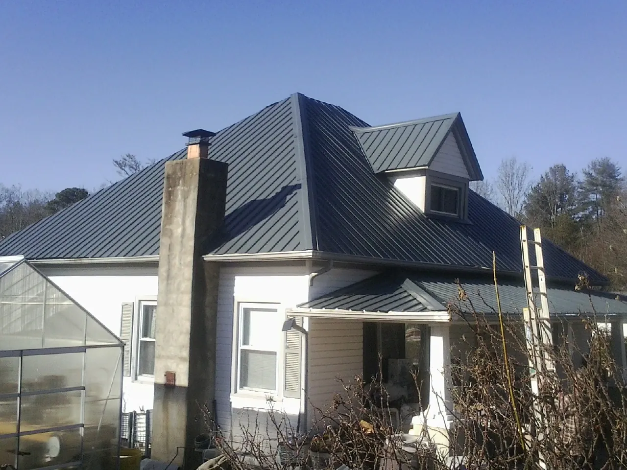 Dark blue standing seam metal roof on a white farmhouse with dormer — Slate & Tile Roof Repair by Roofing Brothers in Congers