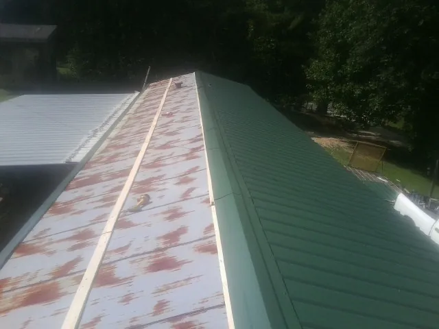Old rusted panels beside newly installed green metal roofing — Wind Damage Roof Repair by Roofing Brothers in Congers