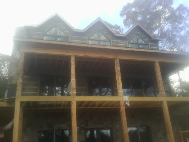 Dormers and porch framing on a large log home under construction — Roof Coating work by our crew in Congers