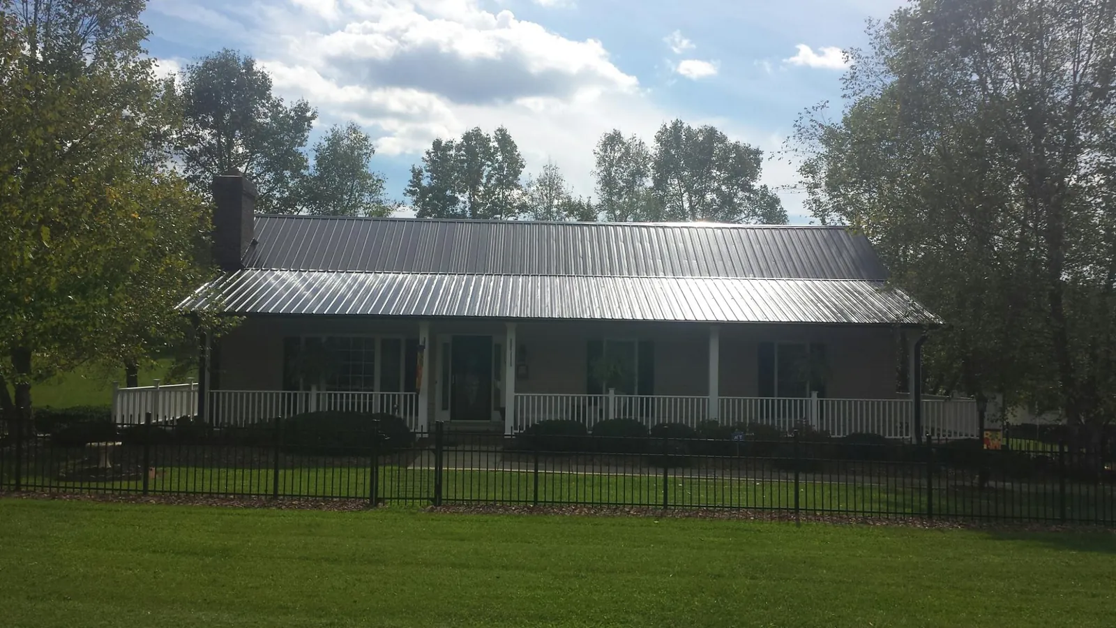 Gray metal roof on a brick ranch with a full width front porch — Gutter Guard Installation work by our crew in Congers