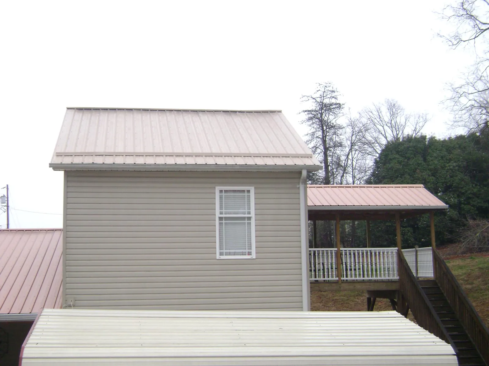 Tan metal roofs on a two story addition and attached porch, from a Roof Replacement job in Congers