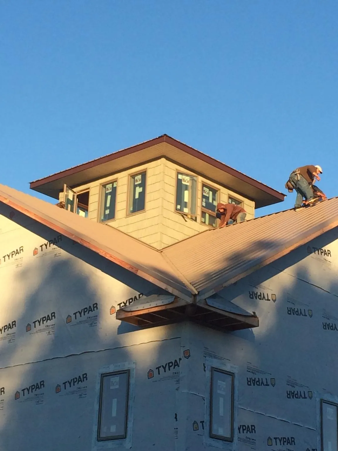 Roofers working around a rooftop cupola on a new metal roof at sunset — Roof Waterproofing in Congers by Roofing Brothers